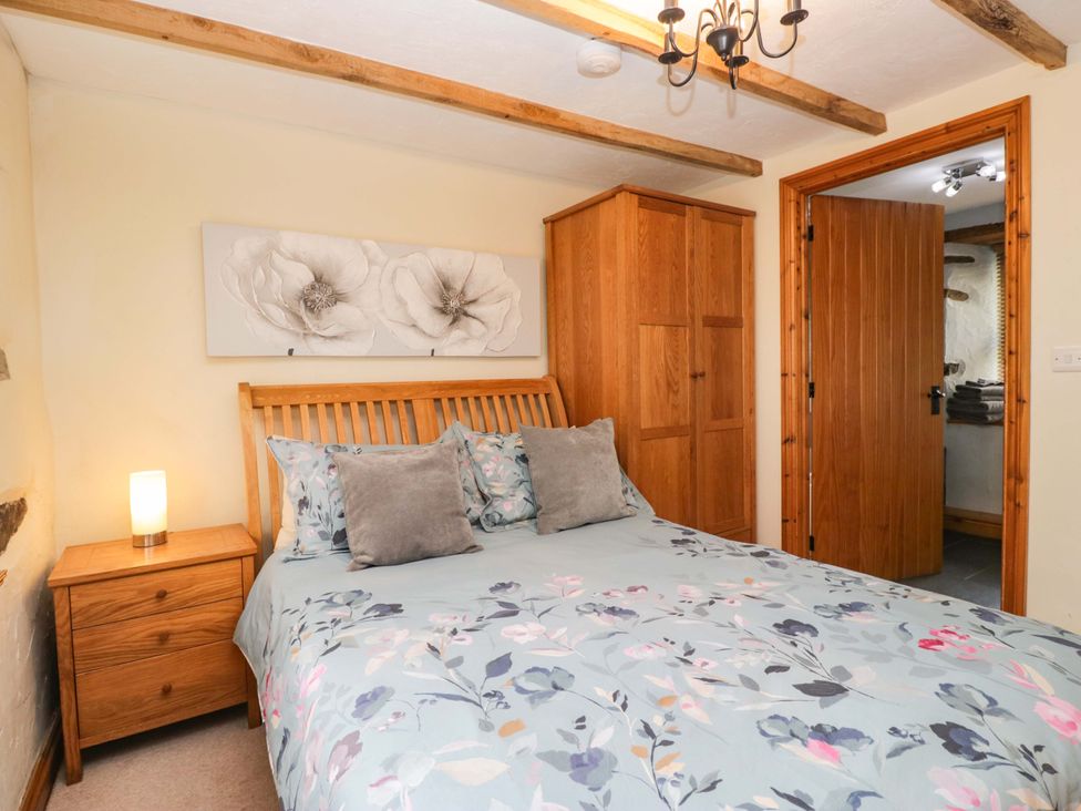 A bedroom with a bed and a wardrobe at Copper Beech Cottage in Torver
