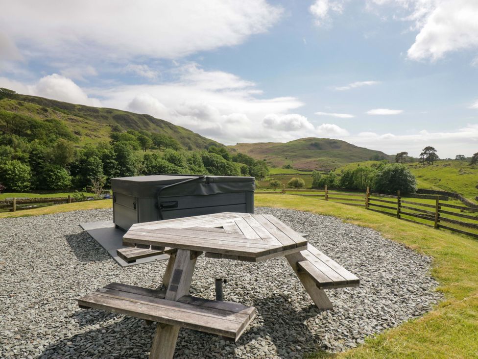 An outdoor area with a hot tub and a picnic table at Copper Beech Cottage in Torver