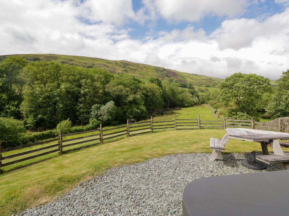 An outdoor view of hills and trees with a bench at Copper Beech Cottage in Torver