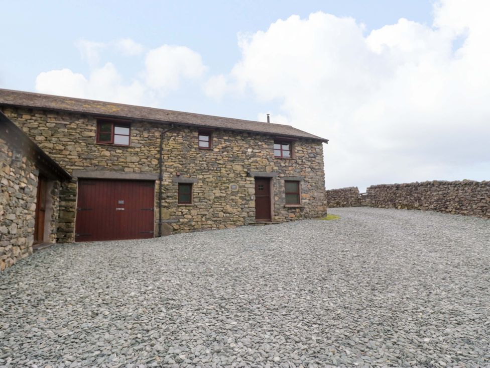 An outdoor view of a stone building with gravel area at Copper Beech Cottage in Torver