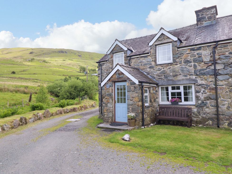 A cottage with a blue door and bench at Stabal Cottage in Dolgellau
