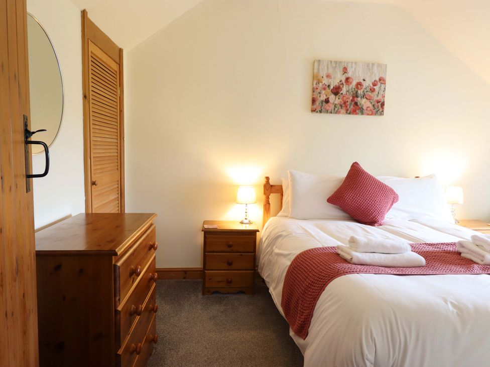 A bedroom with a bed and wooden furniture at Stabal Cottage Dolgellau