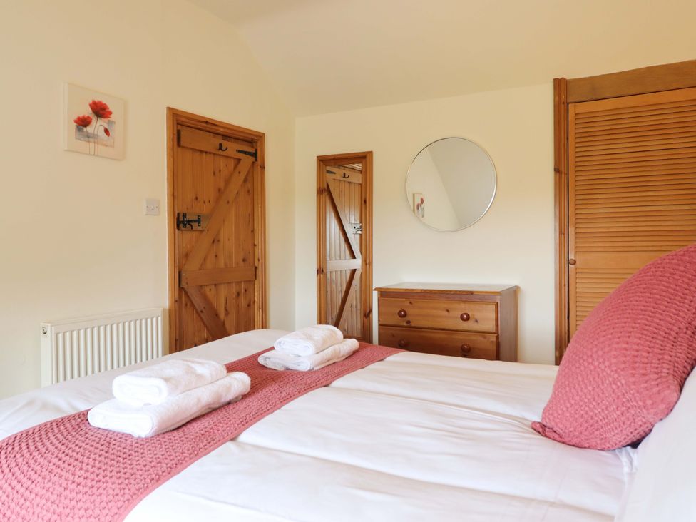 A bedroom with a bed and wooden furniture at Stabal Cottage in Dolgellau