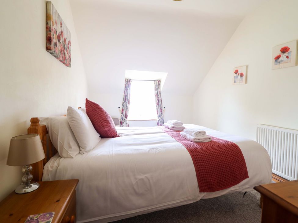 A bedroom with a bed and window at Stabal Cottage in Dolgellau