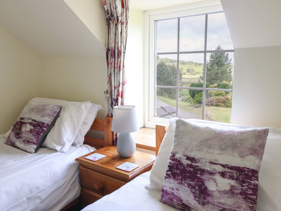 A bedroom with two beds and a window overlooking gardens at Stabal Cottage in Dolgellau
