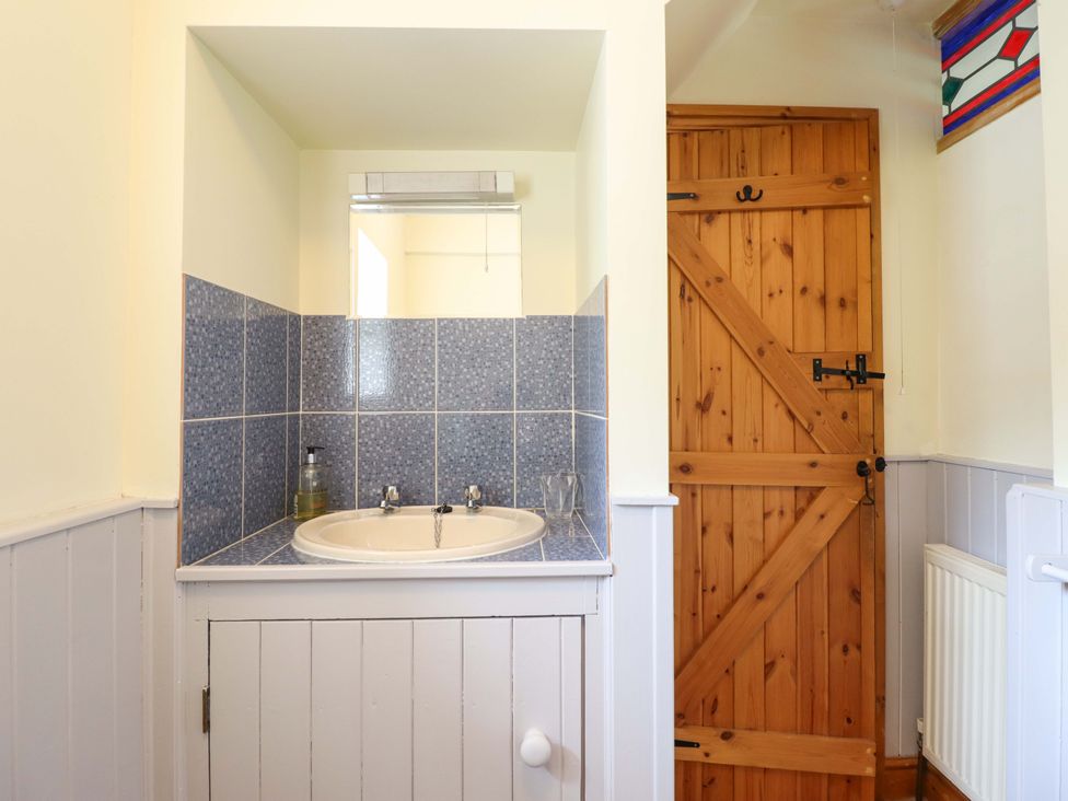 A sink and mirror in a bathroom at Stabal Cottage in Dolgellau