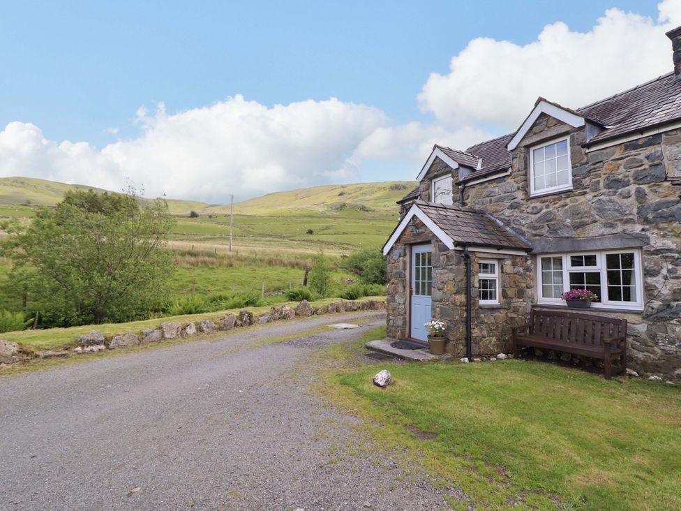 A cottage with a gravel path and bench at Stabal Cottage in Dolgellau