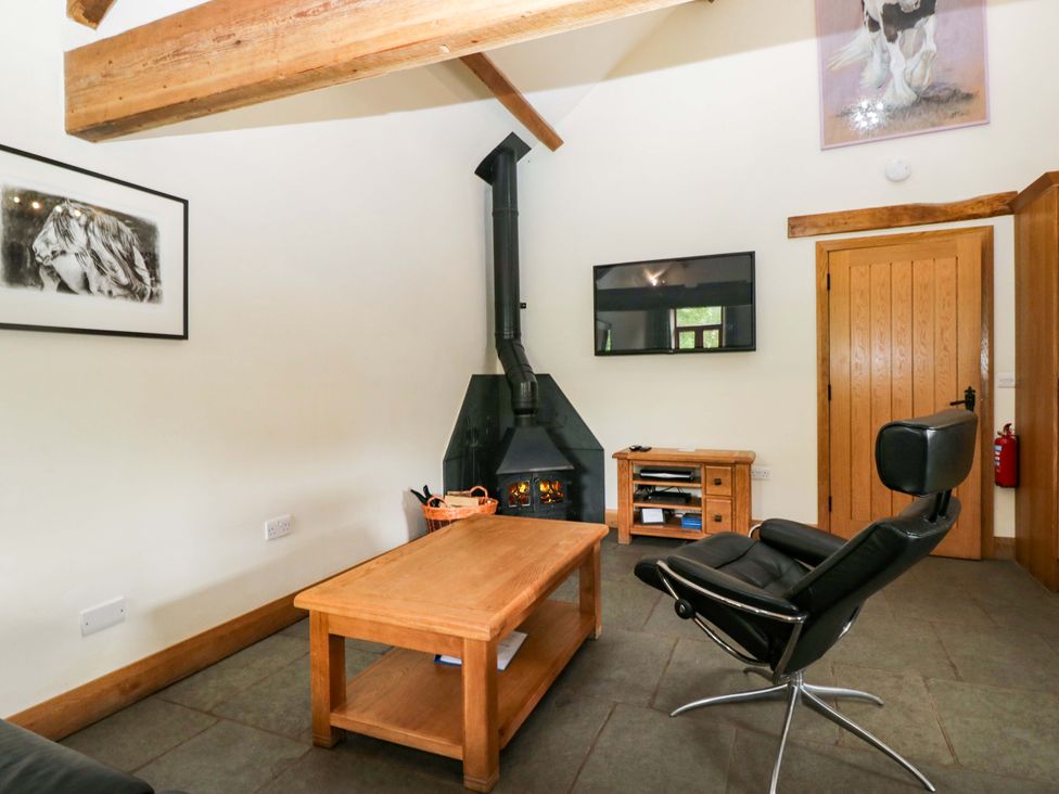 A living room with a fireplace and furniture at Yew Tree Cottage in Torver