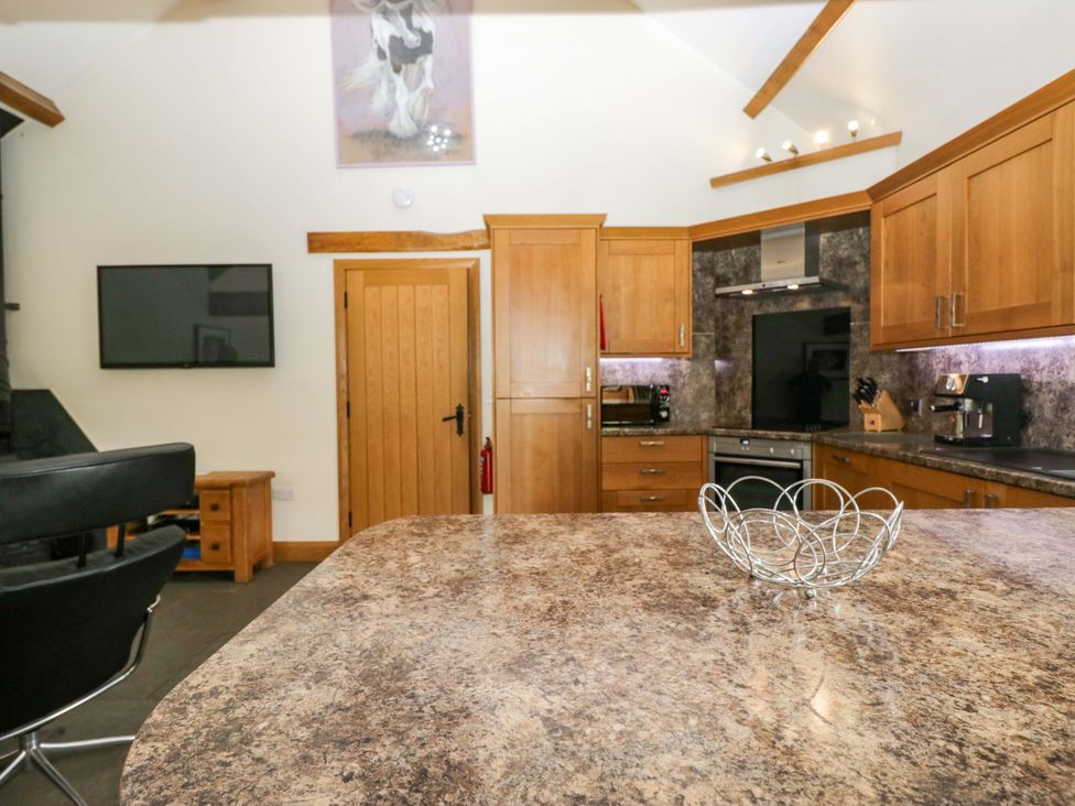 A kitchen with wooden cabinets and appliances at Yew Tree Cottage in Torver