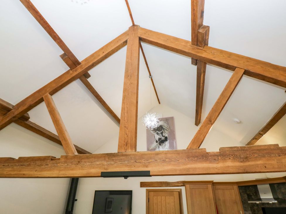 A view of wooden beams and light fixture in a living room at Yew Tree Cottage in Torver