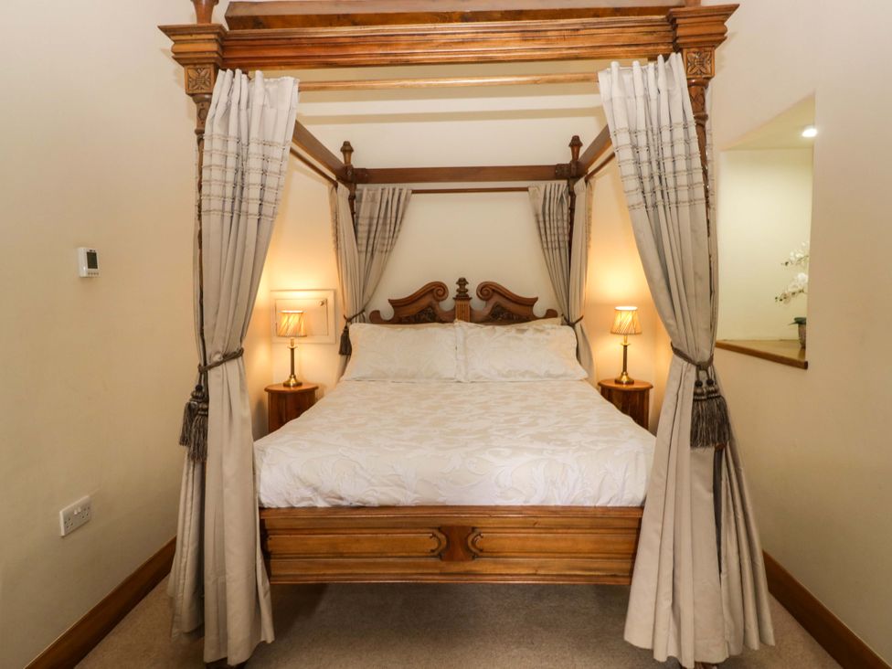 A four-poster bed with bedside lamps at Yew Tree Cottage in Torver