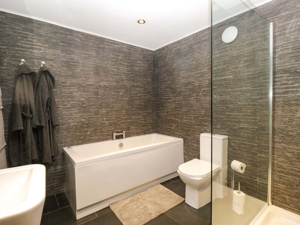A bathroom with a bathtub, toilet, and shower at Yew Tree Cottage in Torver