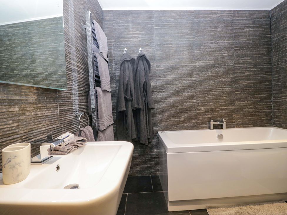 A bathroom featuring a bathtub and sink at Yew Tree Cottage in Torver