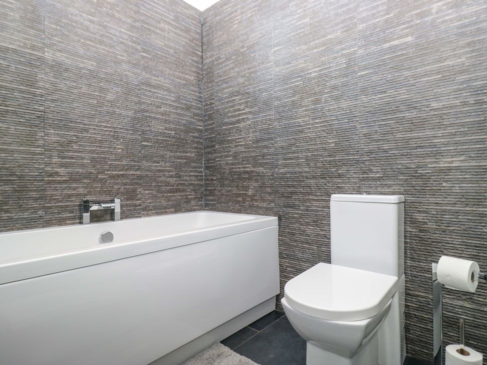 A bathroom with a bathtub and toilet at Yew Tree Cottage in Torver