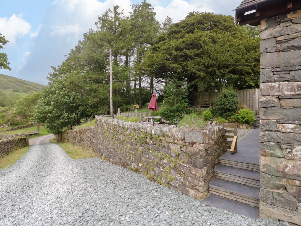 A garden area with a stone wall and seating at Yew Tree Cottage in Torver