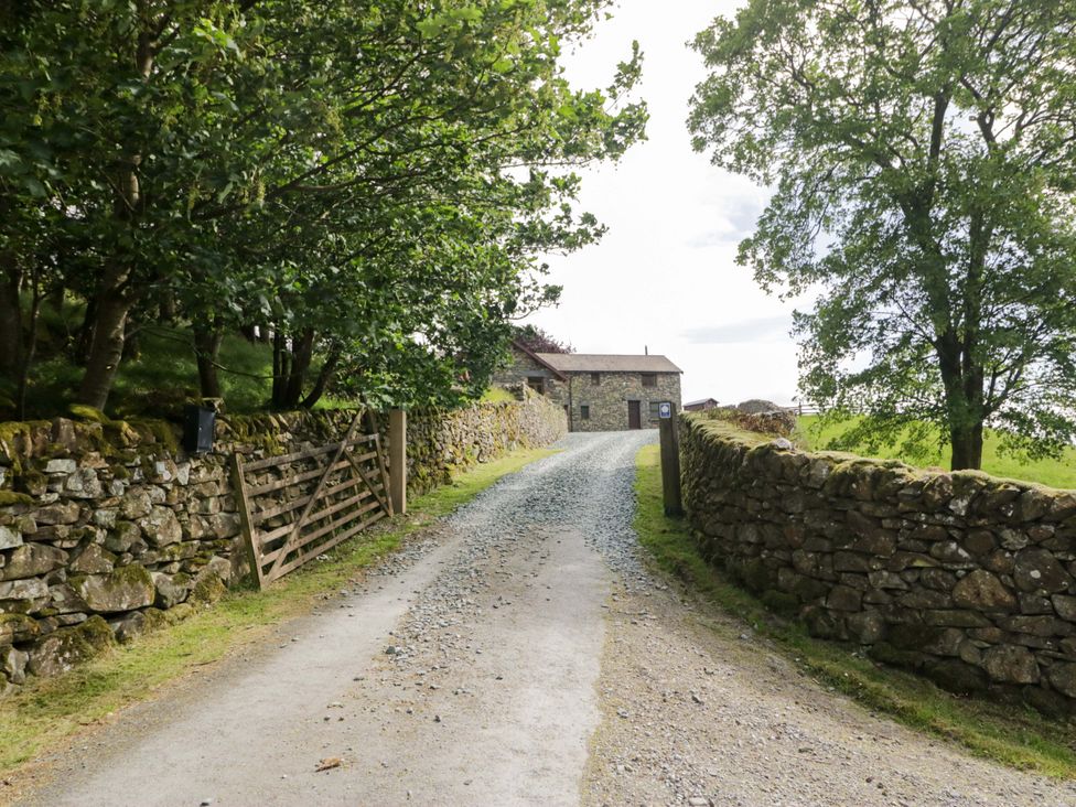 A gravel path leading to a cottage surrounded by trees at Yew Tree Cottage in Torver