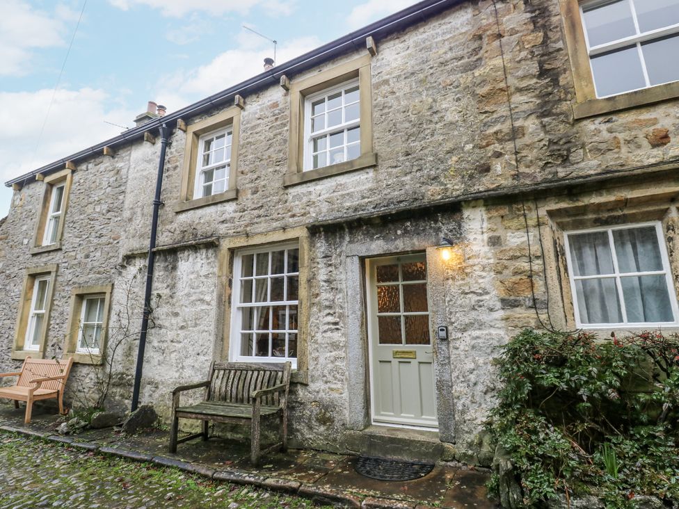 A stone house with a door and benches at Chamber End Fold Grassington