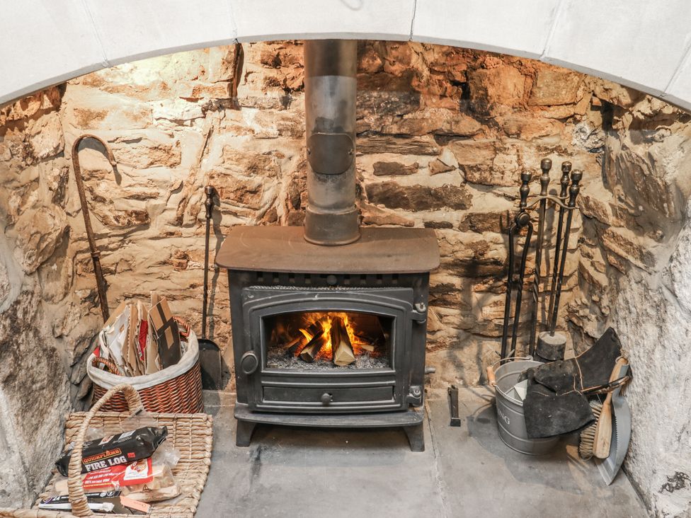 A wood stove with burning logs and accessories at Chamber End Fold in Grassington