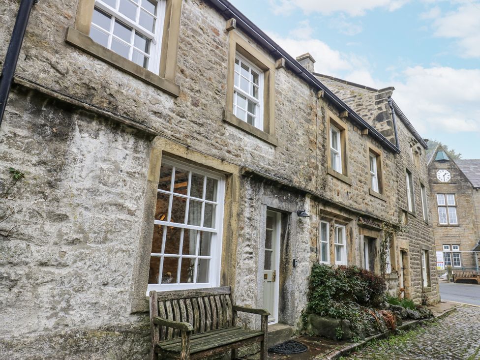 A stone house with windows and a bench at Chamber End Fold Grassington