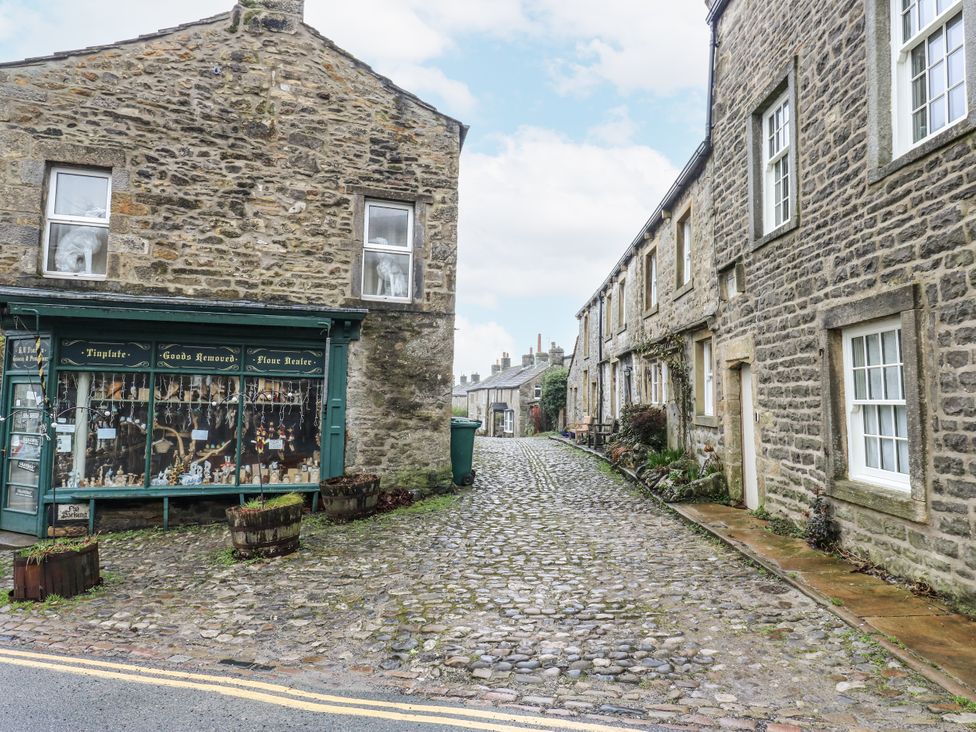 A street with stone buildings and a shopfront at Chamber End Fold in Grassington
