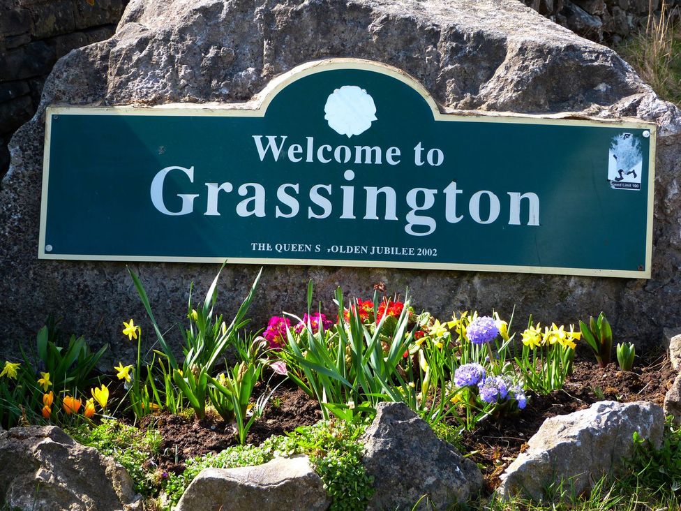 A welcome sign to Grassington with flowers at Chamber End Fold Grassington