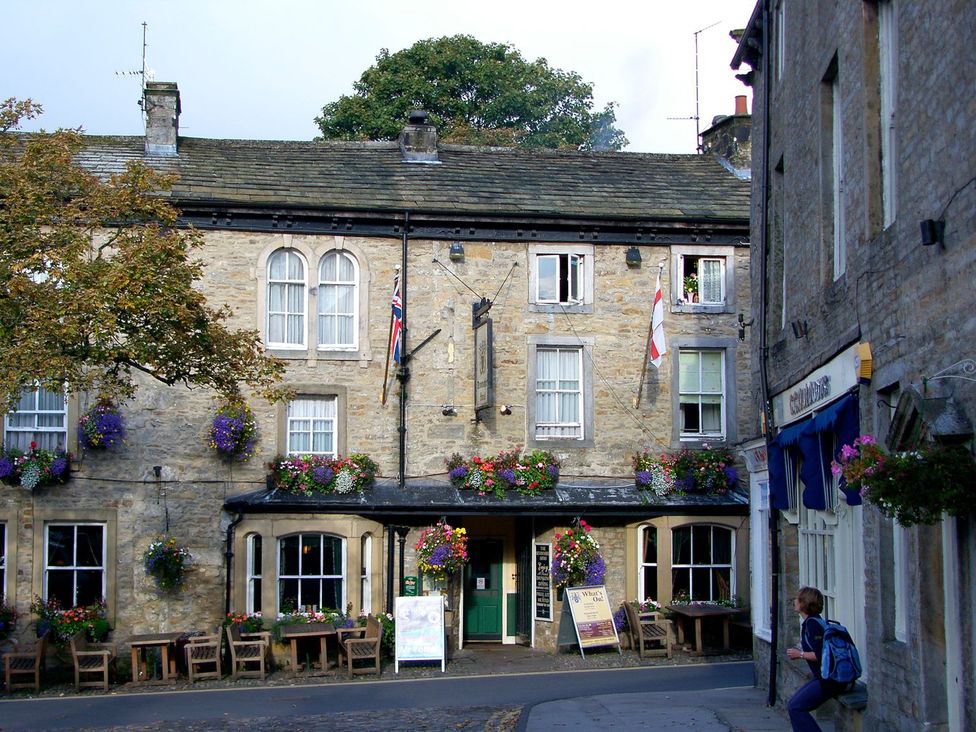 A stone building with windows and flower pots at Chamber End Fold in Grassington