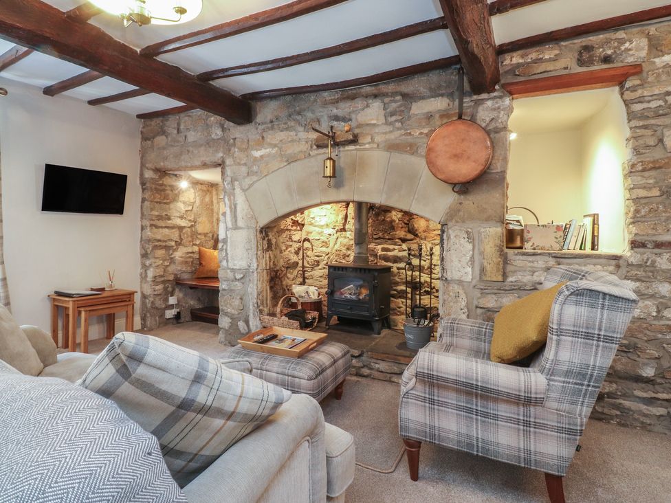 A living room with a stone wall and wood stove at Chamber End Fold Grassington
