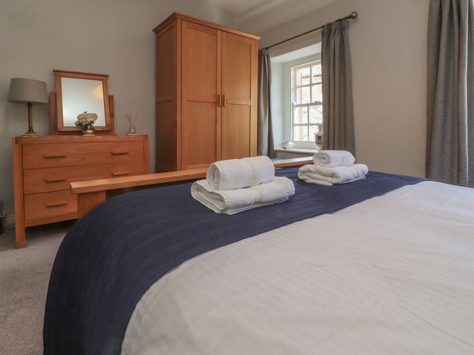 A bedroom with a bed and dresser at Chamber End Fold Grassington