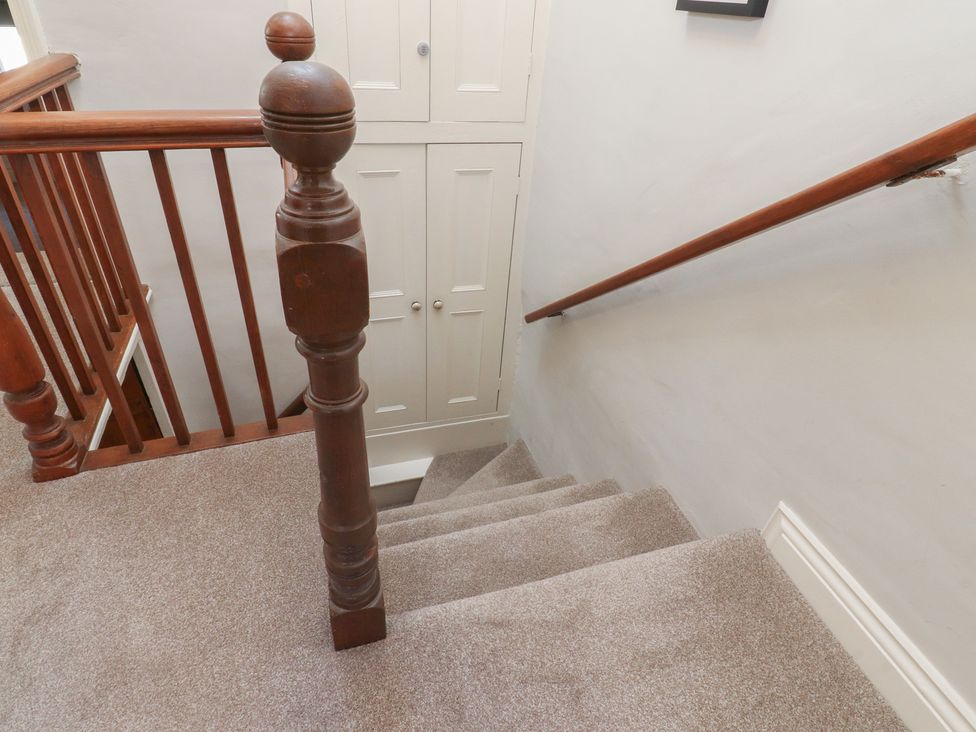 A staircase with wooden handrail and cupboard at Chamber End Fold in Grassington