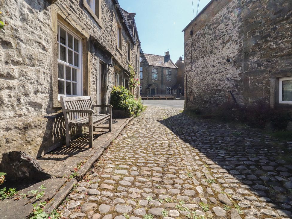 An outdoor area with a cobblestone path and a bench at Chamber End Fold Grassington