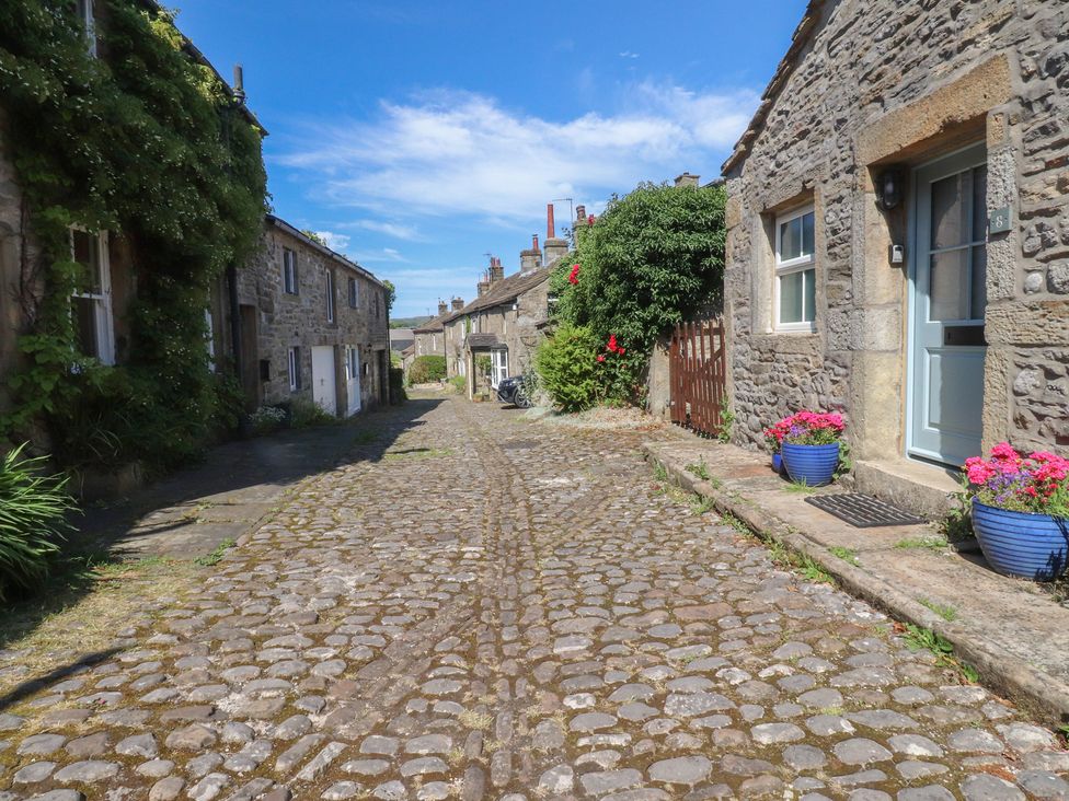 A cobblestone road with stone houses and flowers at Chamber End Fold Grassington