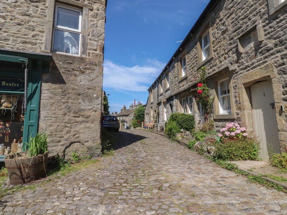 A cobblestone street with stone buildings and a shop front at Chamber End Fold Grassington