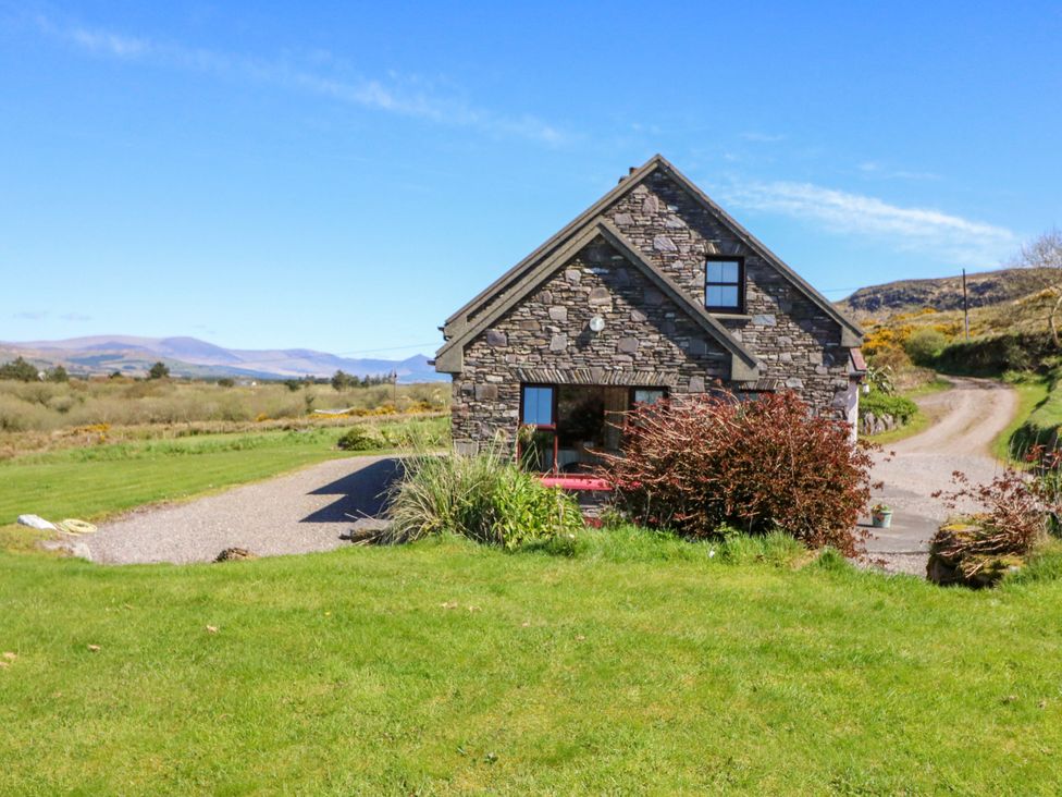 A house with a driveway and grass surrounding it at Stone Cottage in Waterville, County Kerry