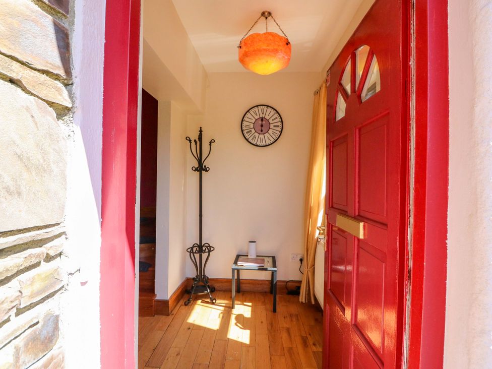 A hallway with a red door and a clock at Stone Cottage in Waterville, County Kerry