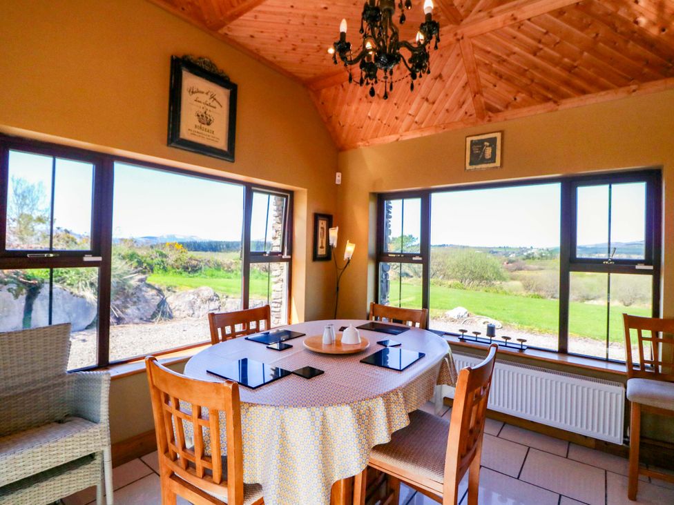 A dining room with a round table and chairs at Stone Cottage Waterville, County Kerry