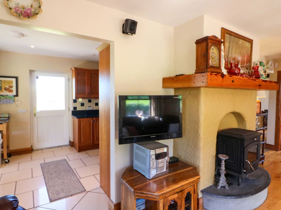 A living room with a television and a stove at Stone Cottage in Waterville, County Kerry