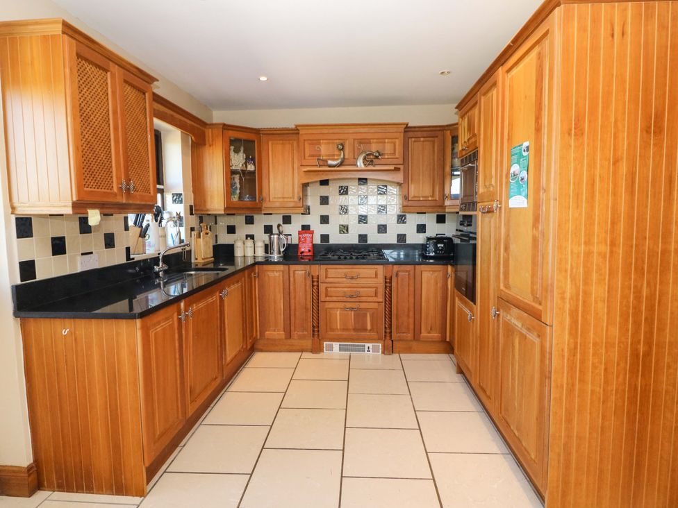A kitchen with wooden cabinets and black countertops at Stone Cottage in Waterville, County Kerry