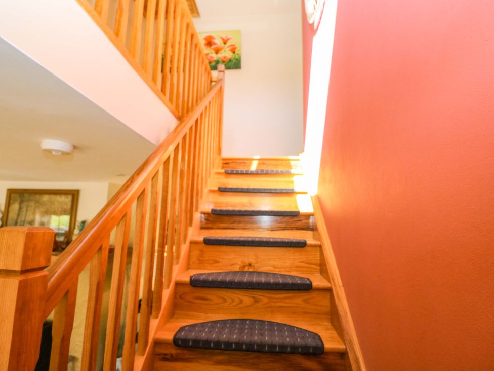 A staircase with wooden railing and artwork at Stone Cottage Waterville, County Kerry