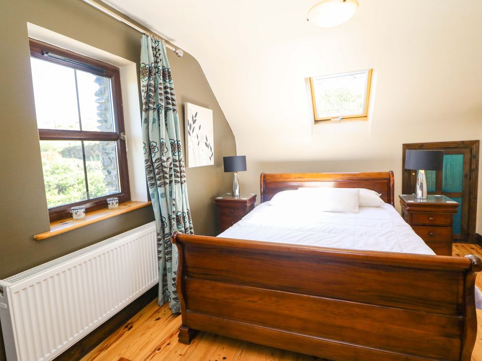 A bedroom with a bed and nightstands at Stone Cottage in Waterville, County Kerry