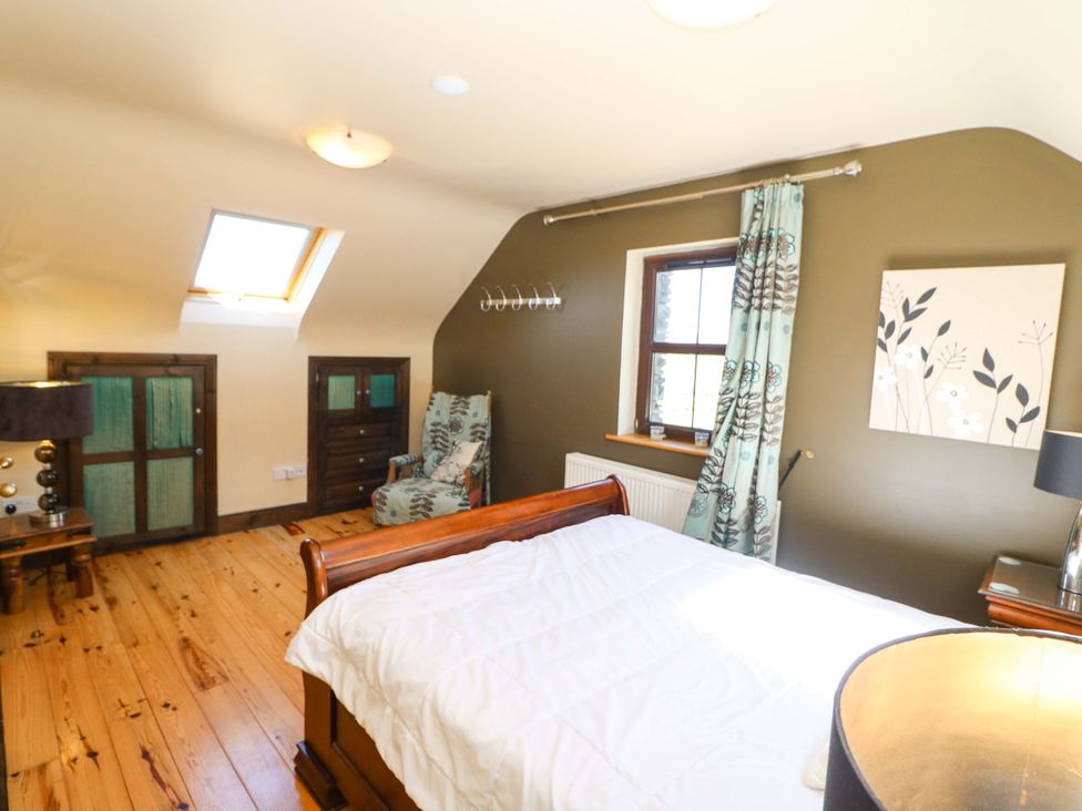 A bedroom with a bed and a lamp at Stone Cottage in Waterville, County Kerry