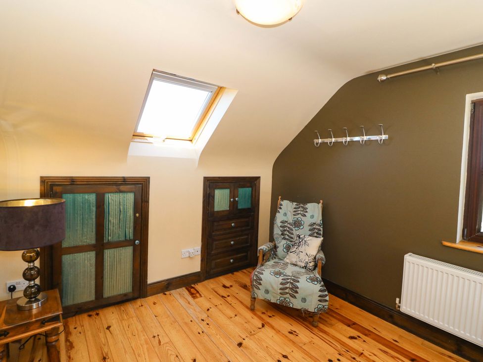 A loft room with a chair and storage at Stone Cottage in Waterville, County Kerry