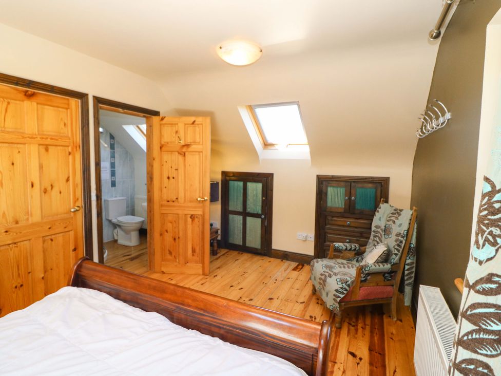 A bedroom with a bed and doors leading to a bathroom at Stone Cottage, Waterville, County Kerry