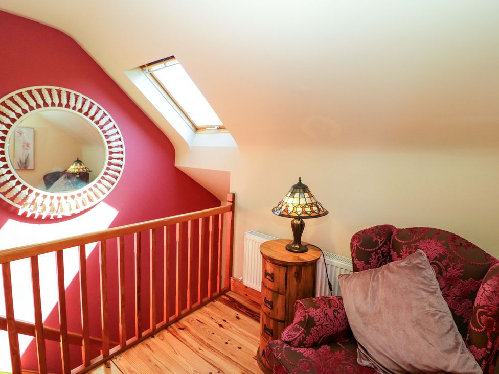 A landing with a lamp and armchair at Stone Cottage in Waterville, County Kerry
