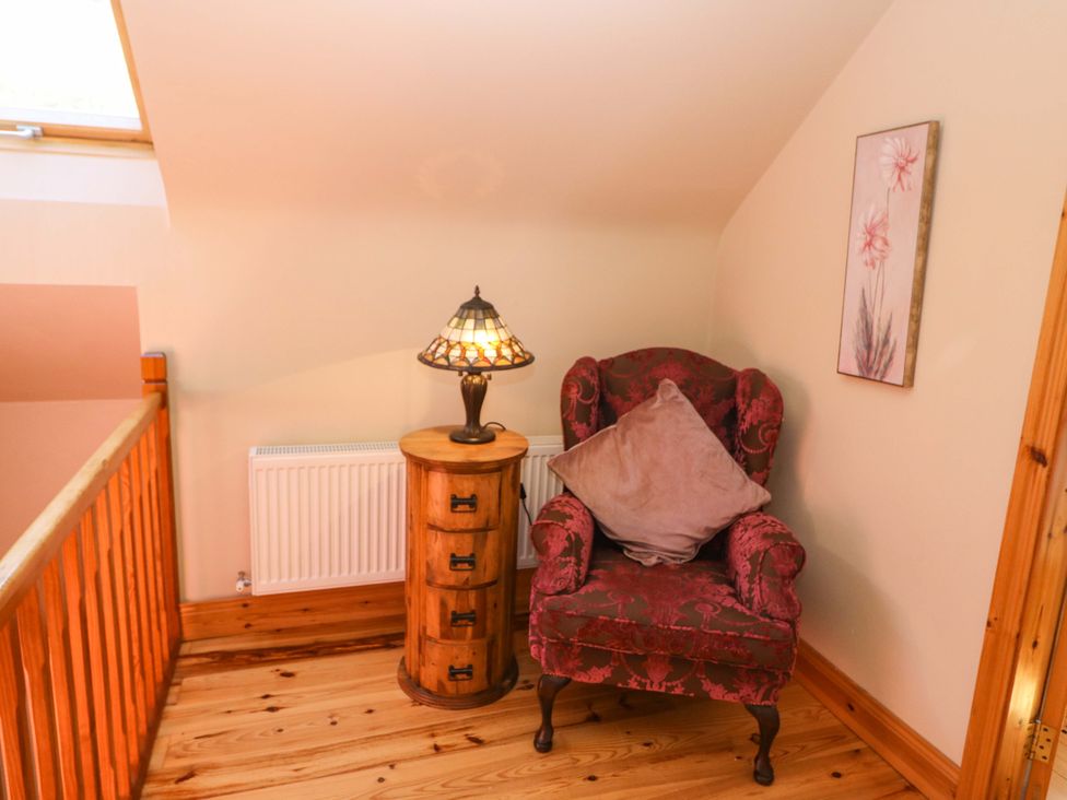 A seating area with a chair and lamp at Stone Cottage in Waterville, County Kerry