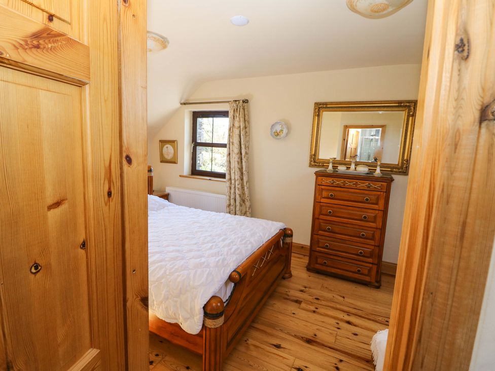 A bedroom with a bed and dresser at Stone Cottage in Waterville, County Kerry