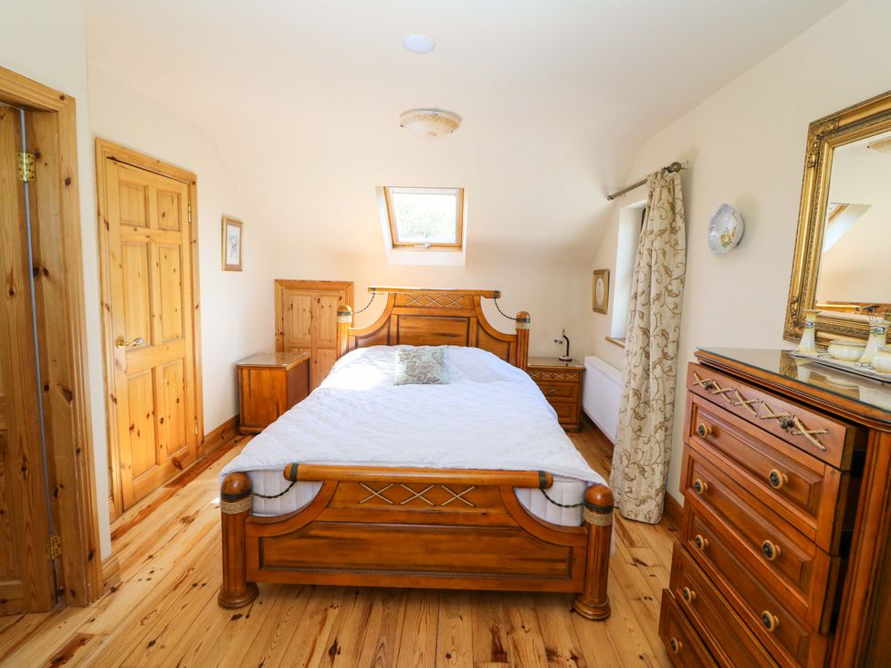 A bedroom with a bed and wooden furniture at Stone Cottage in Waterville, County Kerry