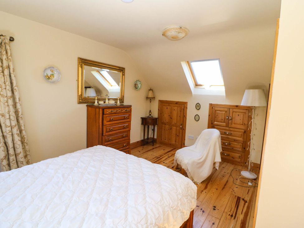 A bedroom with bed and wooden furniture at Stone Cottage, Waterville, County Kerry