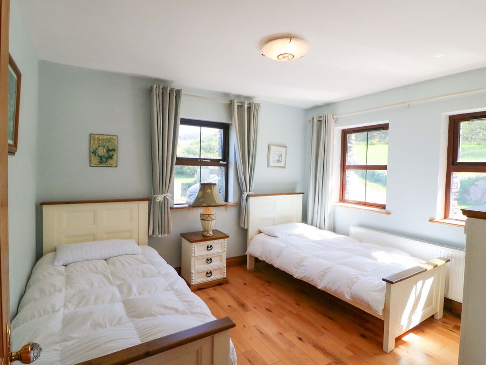 A bedroom with two beds and a lamp at Stone Cottage in Waterville, County Kerry