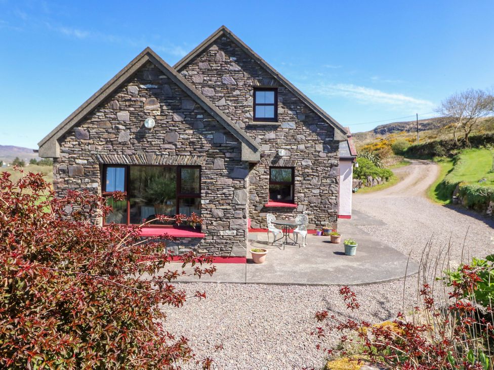 A stone house with a table and chairs outside at Stone Cottage in Waterville, County Kerry