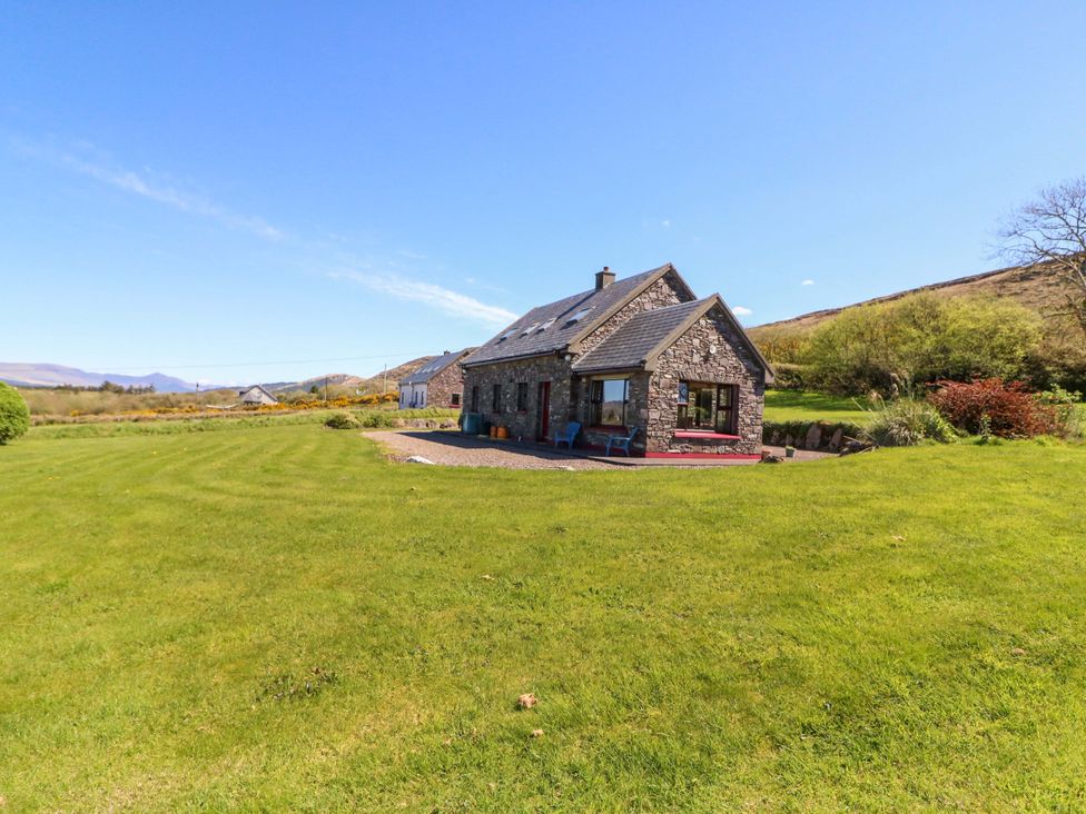A stone house with garden and mountains in the background at Stone Cottage, Waterville, County Kerry